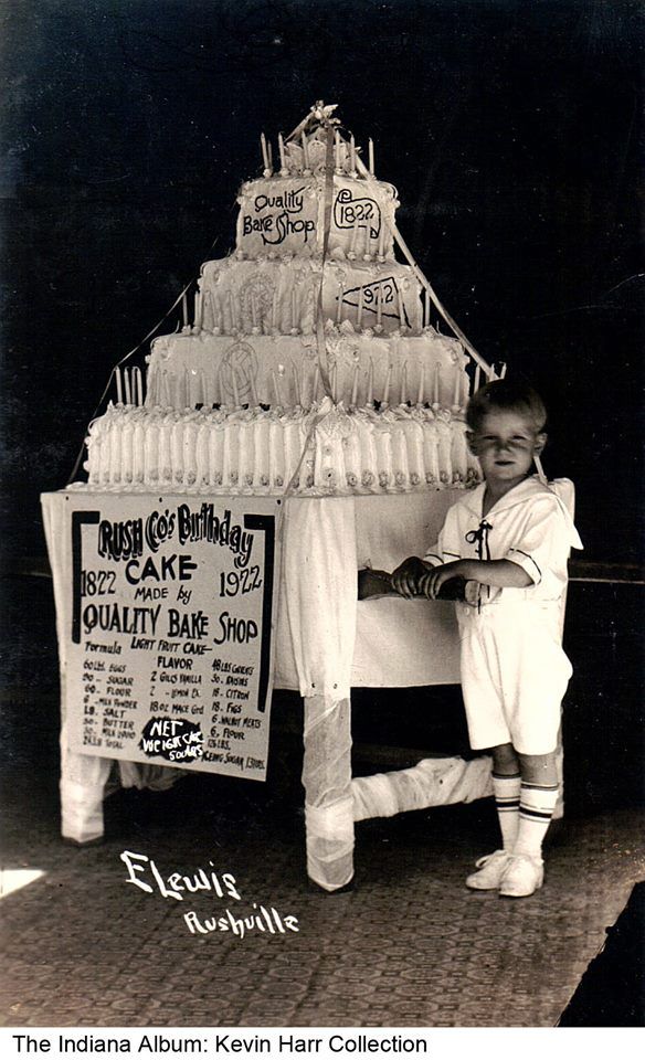 1922 photo of little boy standing next to 500 pound fruit cake with 100 candles. From the Indiana Album: Kevin Harr Collection (facebook). Photo credit: E. Lewis, Rushville