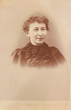 Head and shoulders photo fo a woman, wearing a frilly dark blouse; photo take at at the Appelquest studio in Midddletown, CT