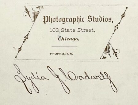 Back of the cabinet card by Lydia J. Cadwell showing woman draped in a lace shawl and headpiece. Has printed signature of Lydia J. Calwell that is slanted to the left, possibly indicating she was left-handed. (Courtesy McIntyre-Culy Collection)
